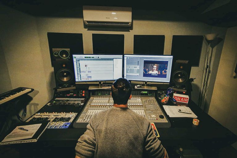 Sala de control con mesa de mezclas y productor trabajando en MainTrack Studio, Barcelona.