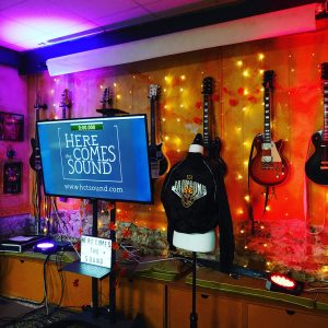 Estudio musical con guitarras colgadas en la pared y luces en Here Comes the Sound, Barcelona