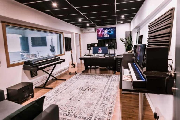 Sala de control con teclados, guitarra y mesa de mezclas, con vistas a la sala de grabación en Koala Studios, Barcelona.
