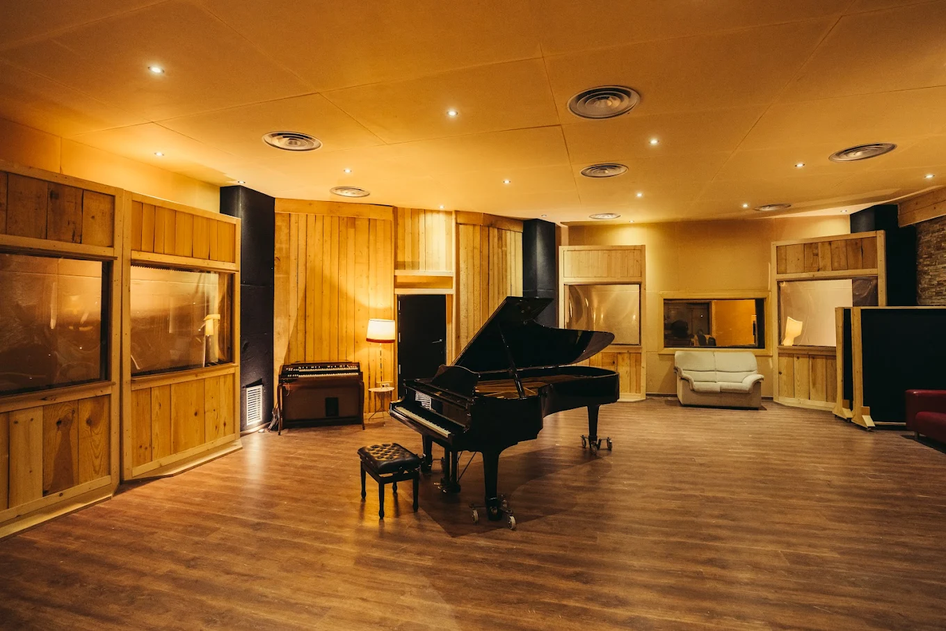 Sala de grabación Estudio Uno, Madrid, con piano negro de cola y madera natural.