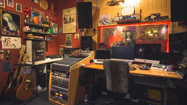 Ministerio del Estéreo en Madrid – sala de control profesional decorada con posters de lobos y anime, neones rojos, guitarras y mesa de mezclas para producción musical.