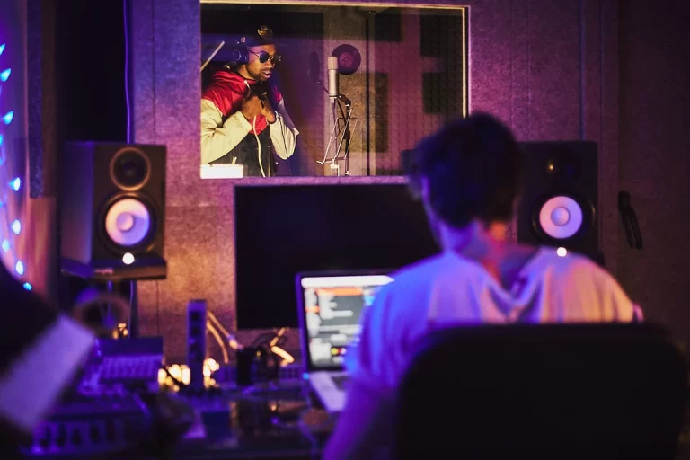 Sala de control de No Cap Estudios en Madrid con productor observando a la cabina de grabación, donde un artista está cantando.