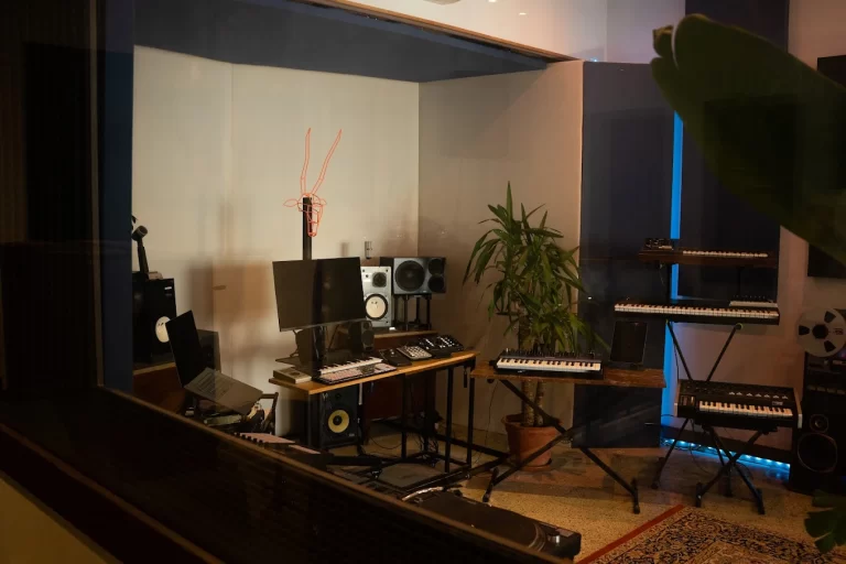Sala de control del estudio Room To Studio en Barcelona vista desde la cabina de grabación con mesa de mezclas y teclados
