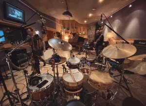 Sala de grabación de Sol de Sants Studios en Barcelona con batería microfoneada, múltiples instrumentos y guitarrista preparándose para sesión