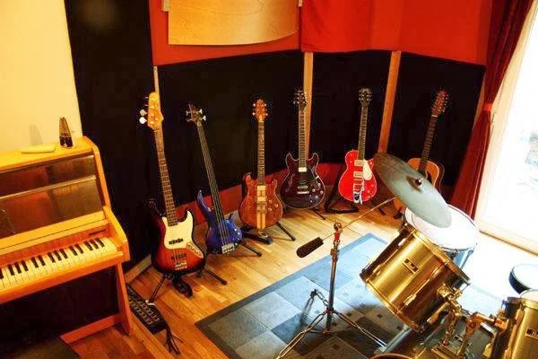 Sala de grabación Tostadero Estudis, Barcelona, con batería, guitarras, bajos y piano de pared.