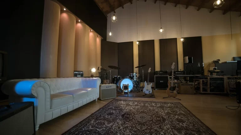 VOL64 Studio, Barcelona — sala de grabación amplia con batería, instrumentos y zona de descanso con sofá.